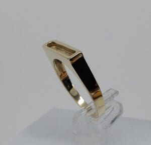 Gold geometric ring on clear stand.
