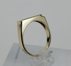 Gold geometric ring on clear stand.