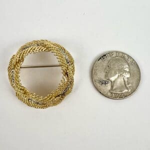 Gold brooch next to a quarter coin.