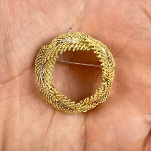 Gold and silver circular brooch in hand.