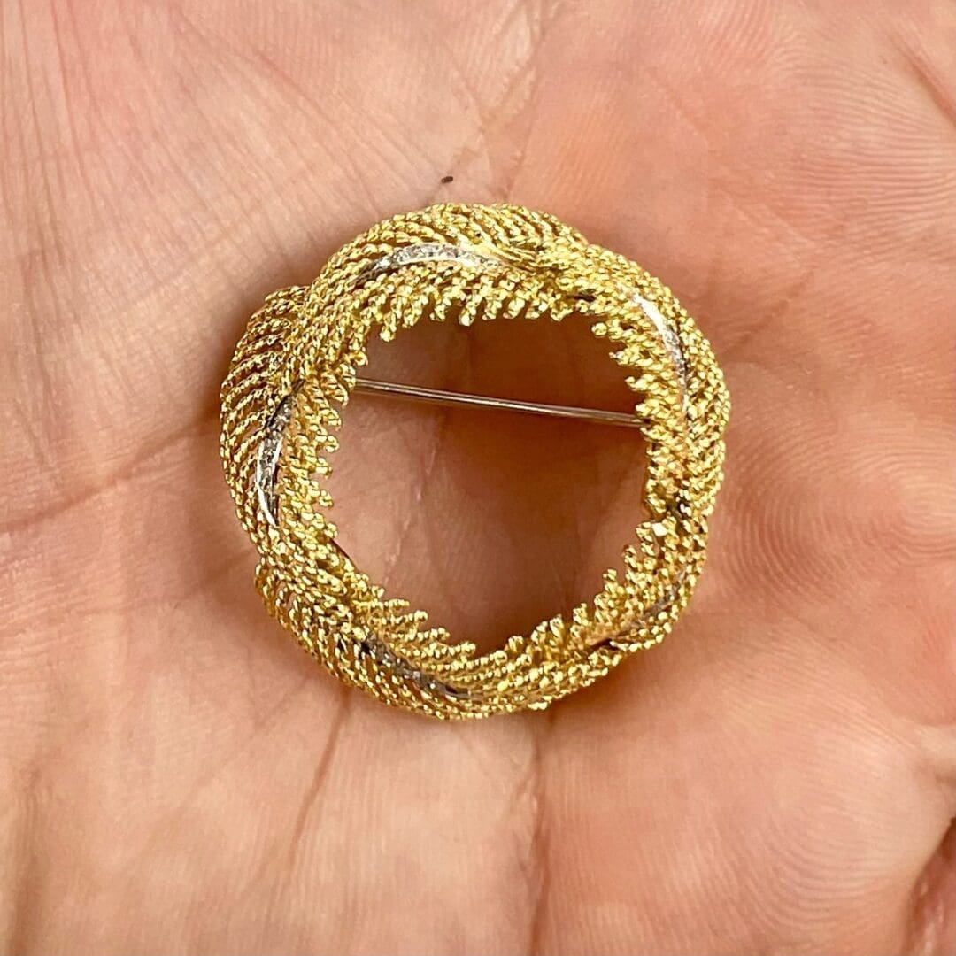 Gold and silver circular brooch in hand.