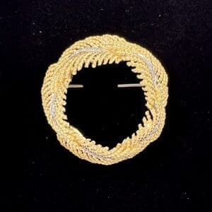 Gold circular brooch with intricate design.