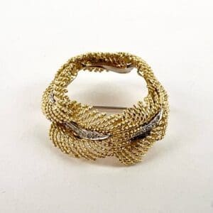 Gold woven brooch with textured design.