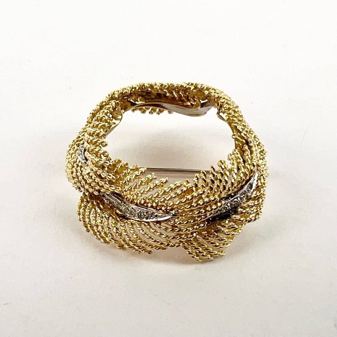 Gold woven brooch with textured design.
