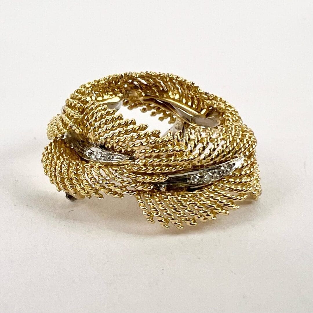 Gold brooch with intricate woven design.