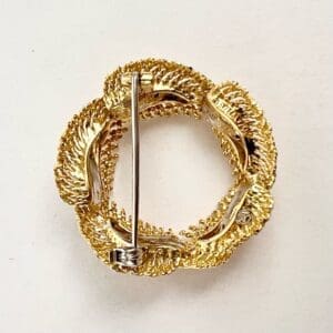 Gold circular brooch with intricate design.