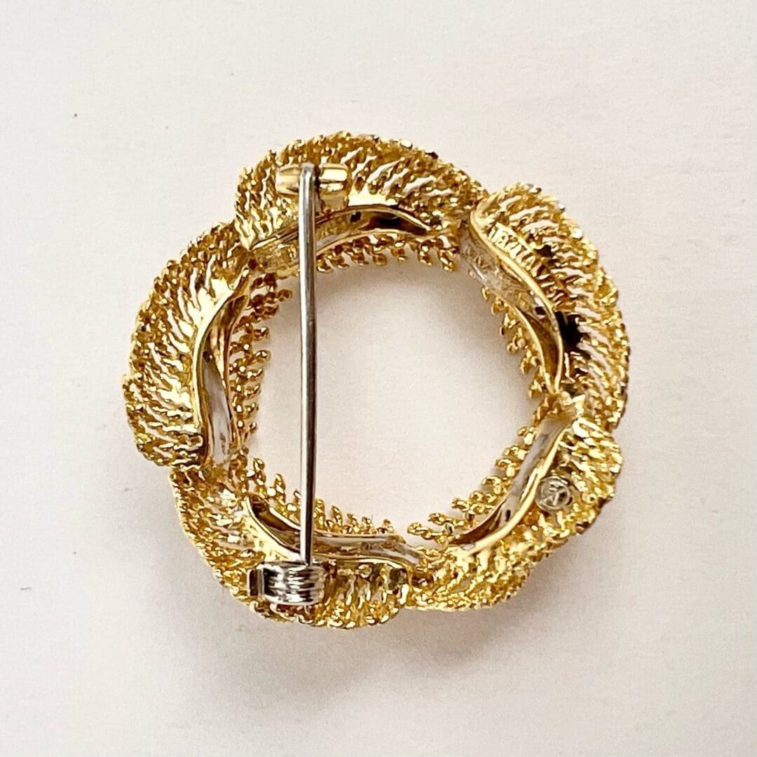 Gold circular brooch with intricate design.