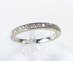 Diamond-studded silver ring on clear stand.
