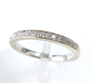 Diamond-studded silver ring on display stand.