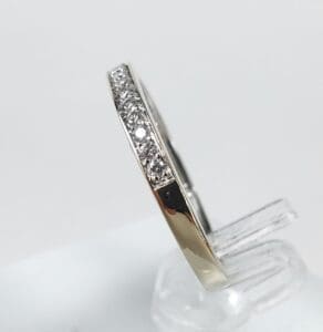 Diamond-studded silver ring on clear stand.