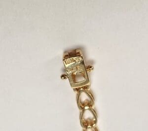 Gold bracelet clasp and chain detail.