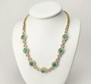 Gold chain necklace with green gemstones.