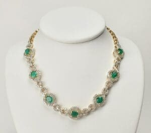 Gold necklace with green gemstones on display.