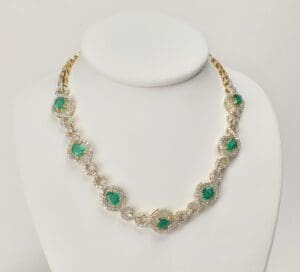 Gold necklace with green gemstones on display.
