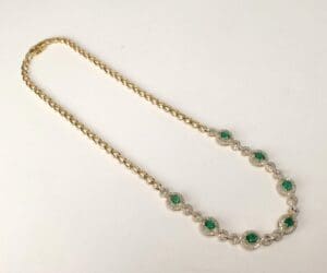 Gold necklace with green gemstones and diamonds.