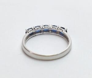 Silver ring with blue gemstones, white background.