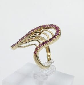 Gold ring with pink gemstones on display.