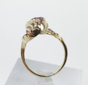 Gold ring with pink gemstones on stand.