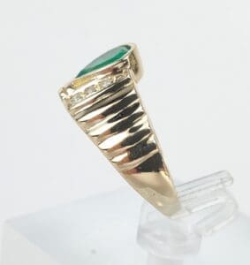 Gold ring with green gemstone on display.