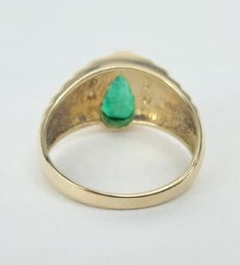 Gold ring with a green gemstone inside.