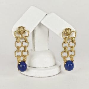 Gold earrings with blue beads displayed elegantly.