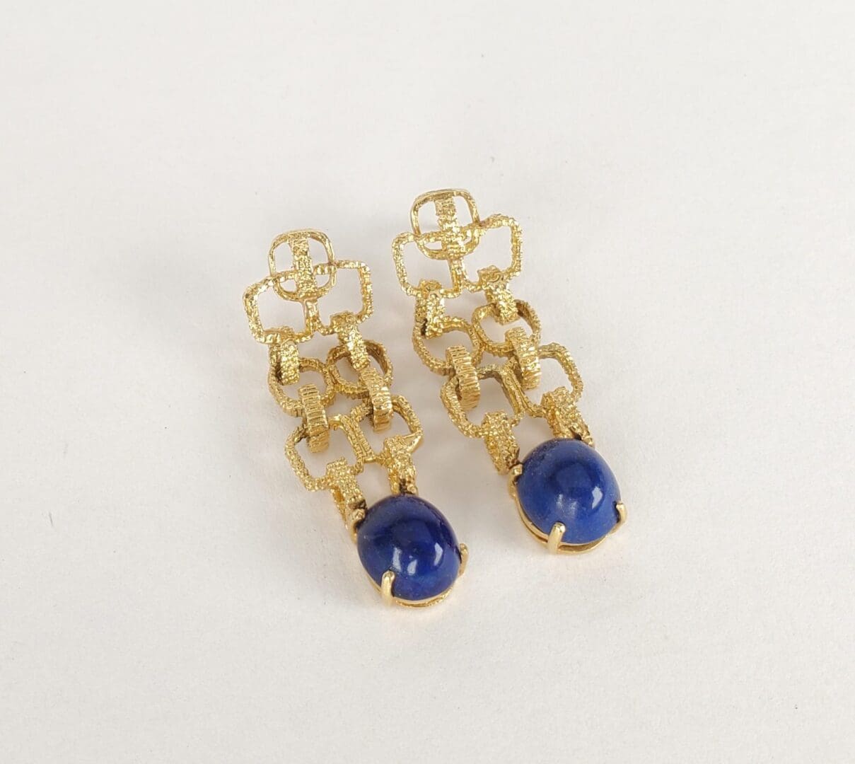Gold earrings with blue gemstone drops.