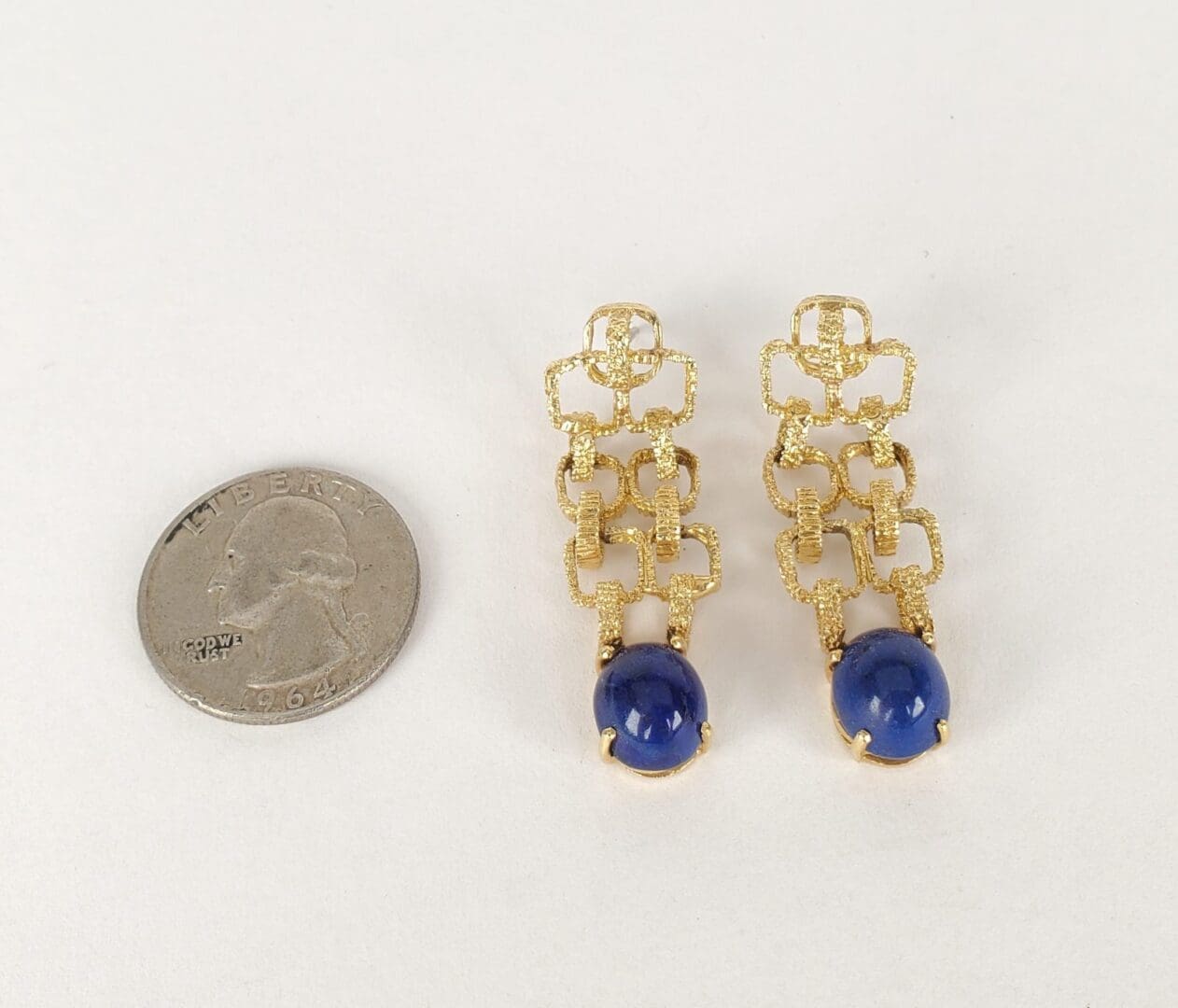 Gold earrings with blue stones, quarter comparison.