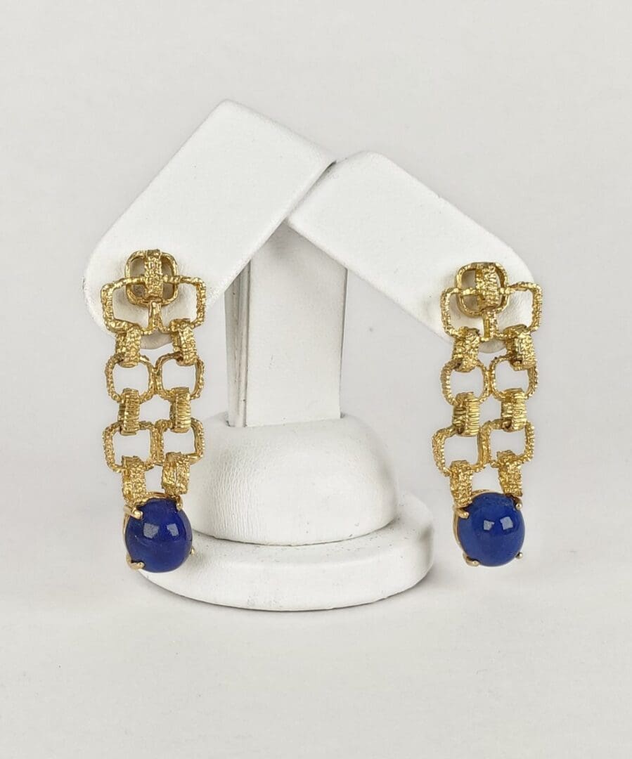 Gold earrings with blue beads displayed elegantly.