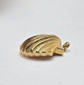 Gold seashell pendant on white background.