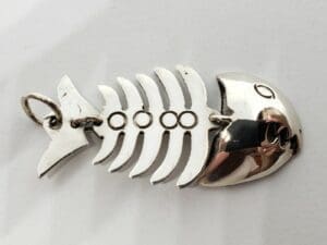 Silver fish skeleton keychain on white background.