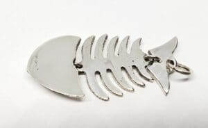 Fish bone skeleton metal pendant on white.