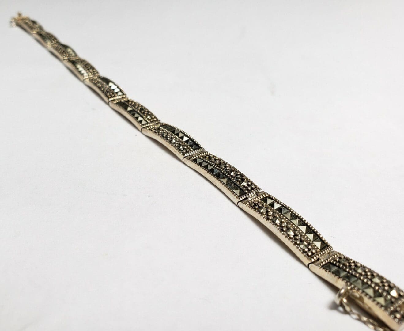 Intricate silver bracelet on white background.