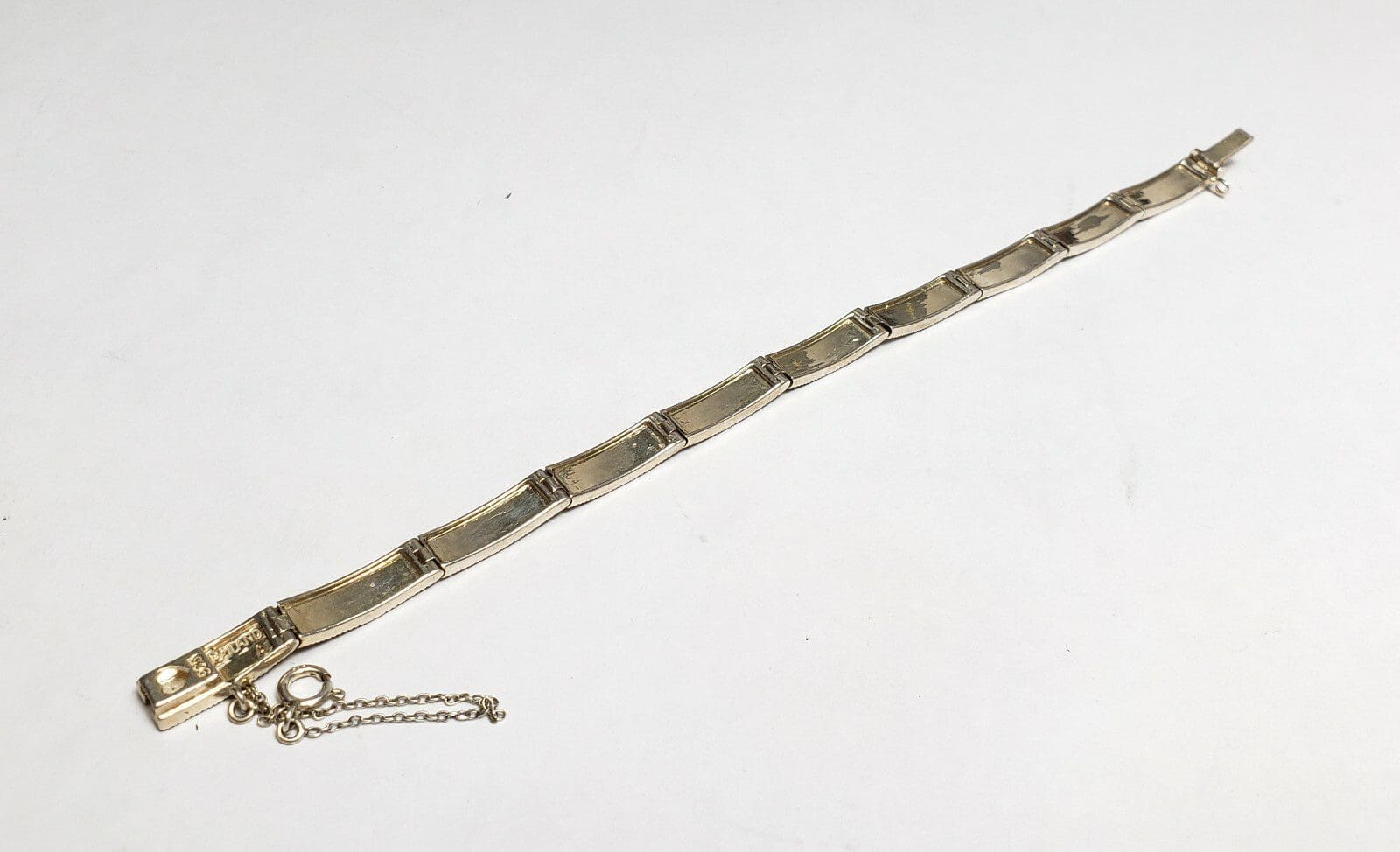 Gold bracelet with chain on white background.