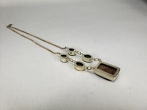 Gold chain with rectangular and oval pendants.