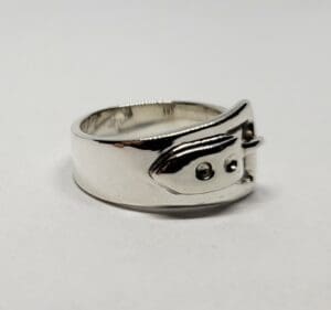 Silver ring with buckle design detail.