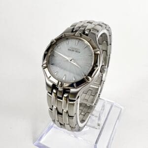 Silver wristwatch with metal bracelet on stand.
