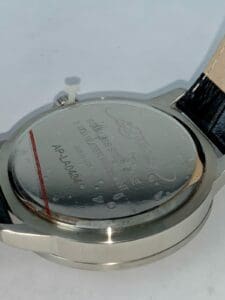 Wristwatch back with engraved text and markings.