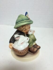 Boy figurine with rabbits in basket.