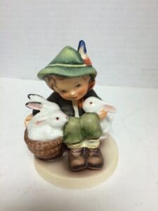 Child figurine with two white rabbits.