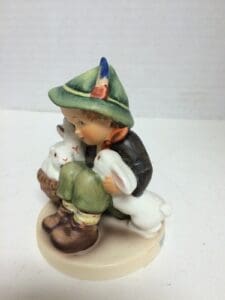 Child figurine with rabbits on a base.