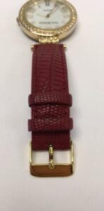 Gold watch with red leather strap.