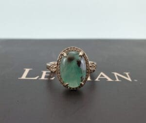 Emerald ring on black surface background.