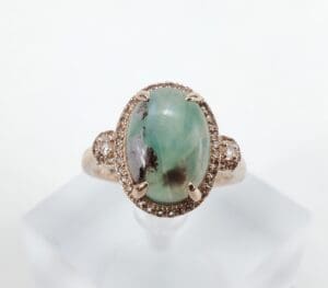 Gold ring with green oval gemstone.
