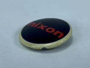 Round pin with "Nixon" in red text.