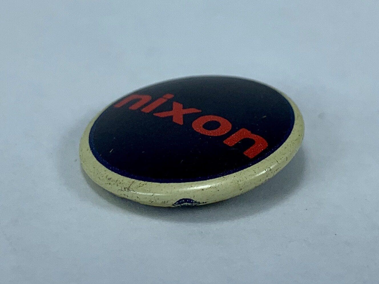 Round pin with "Nixon" in red text.