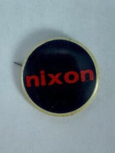 Round pin with red text "nixon".