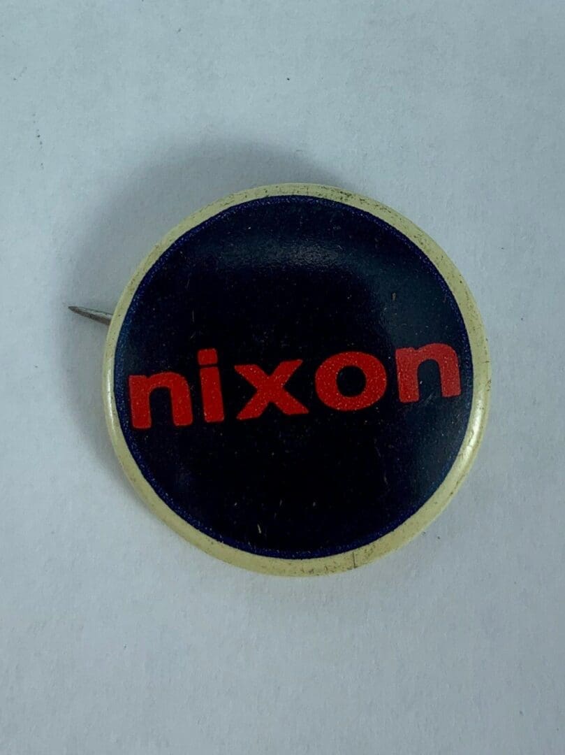 Round pin with red text "nixon".