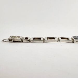 Silver bracelet with rectangular dark inlays.