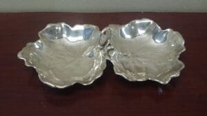 Silver leaf-shaped double dish on table.