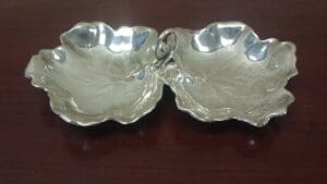 Silver leaf-shaped double dish on table.